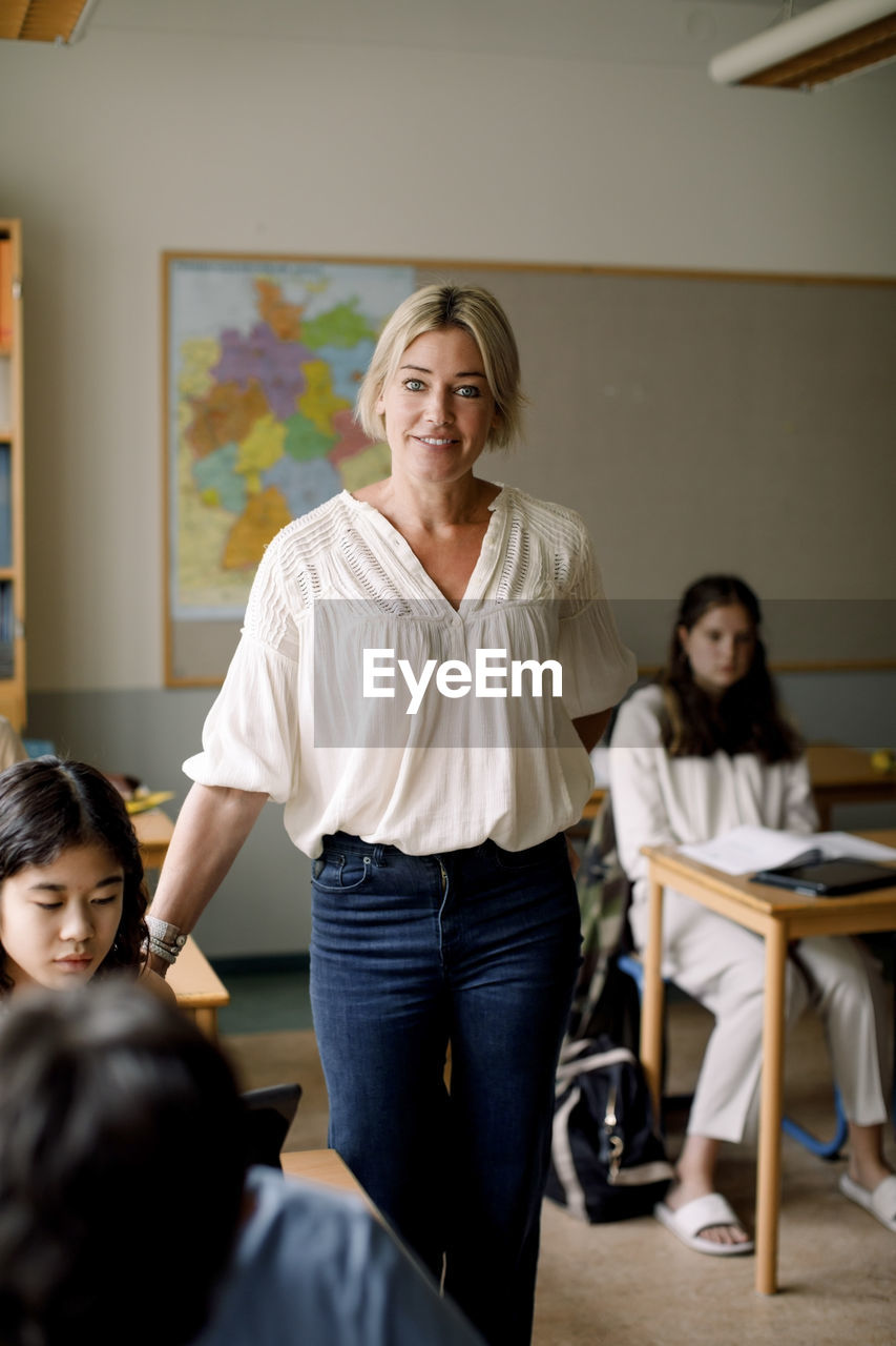 Portrait of female teacher standing in high school classroom