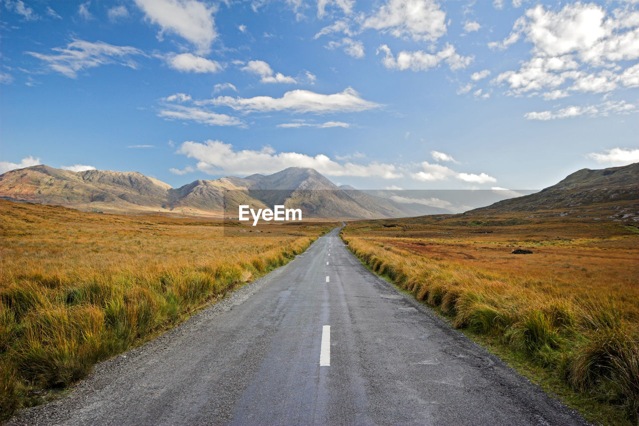 Road leading towards mountains against sky