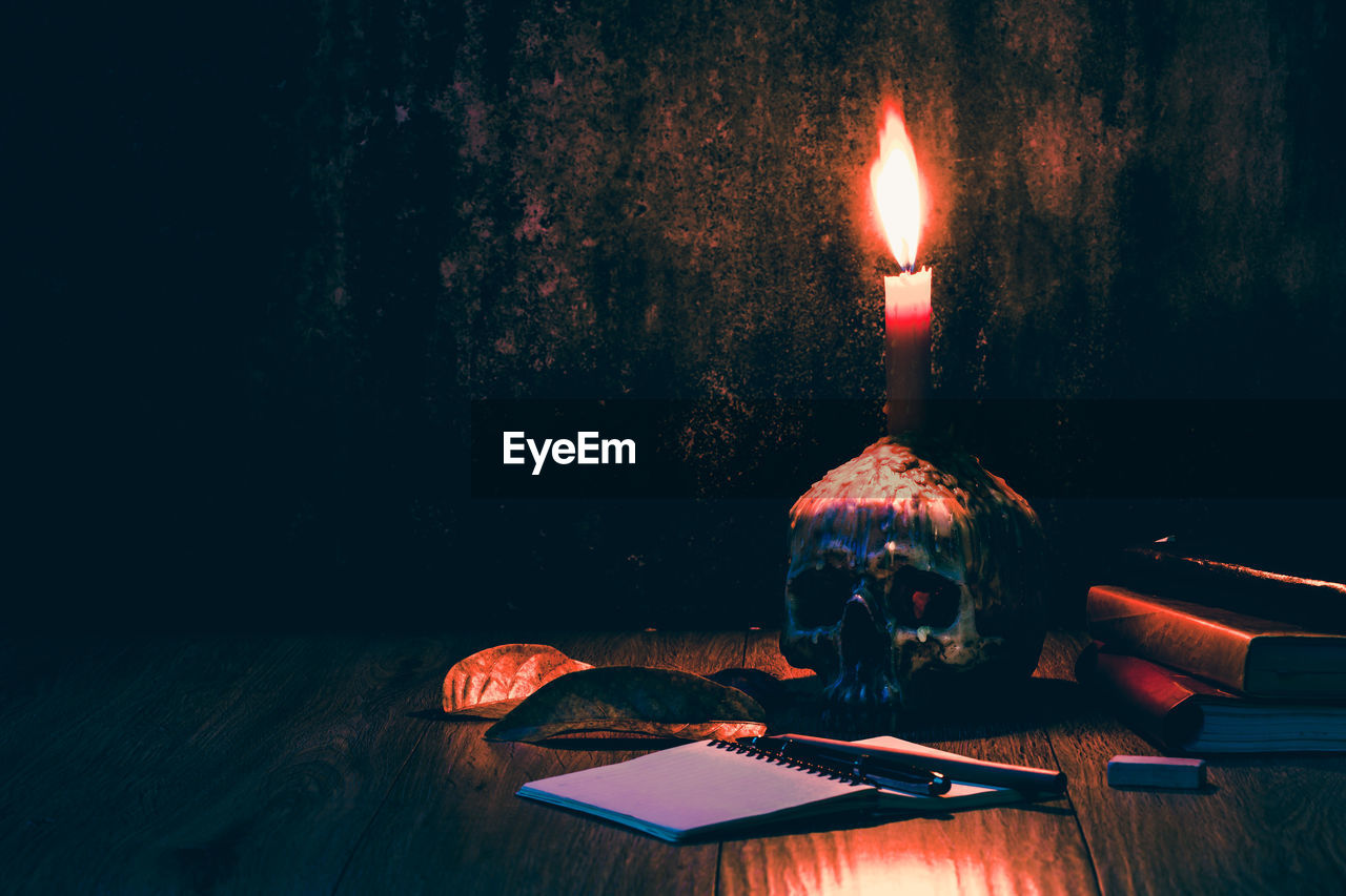 Illuminated candle on human skull over table