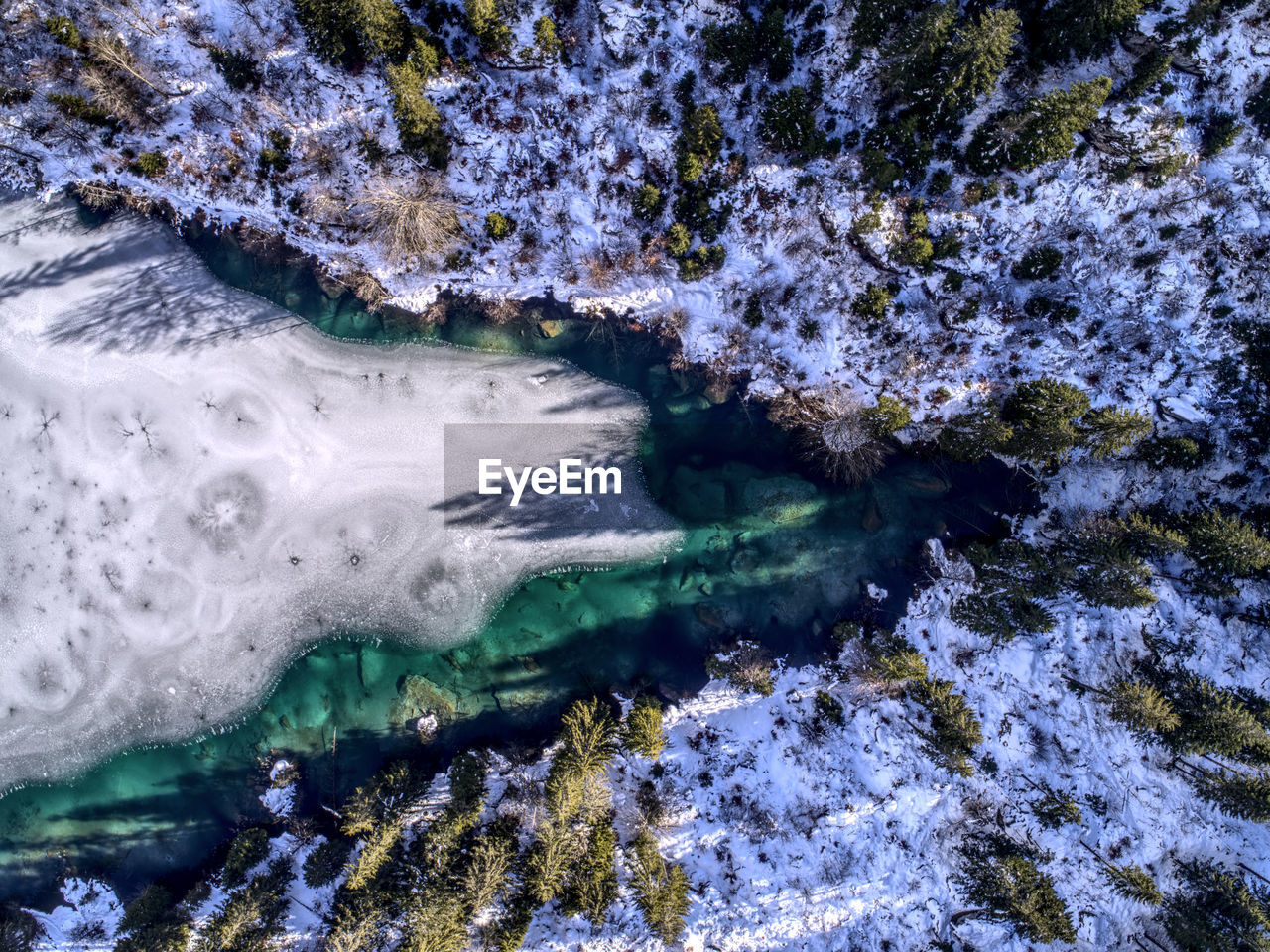 High angle view of lake by snow covered forest during winter