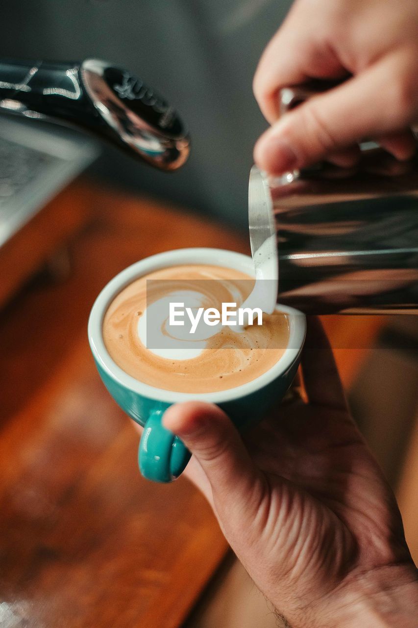 Cropped hands of person preparing coffee at cafe