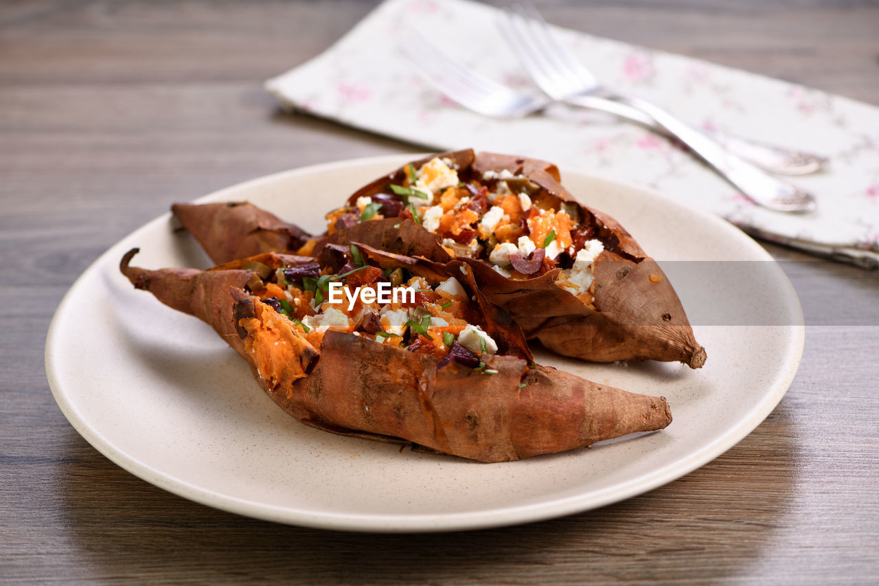 Baked sweet potato stuffed with chopped sun-dried tomatoes, olives, feta cheese and basil  
