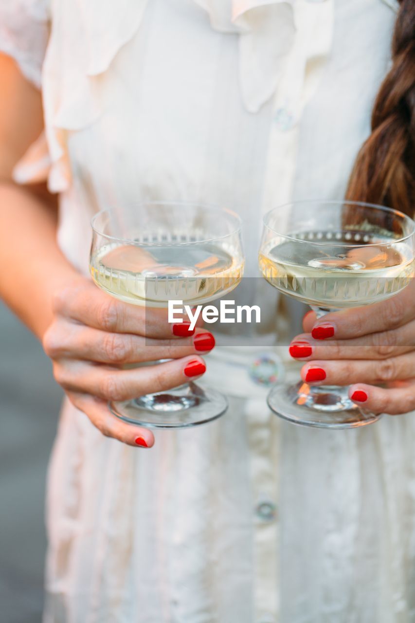 Midsection of woman holding wineglasses