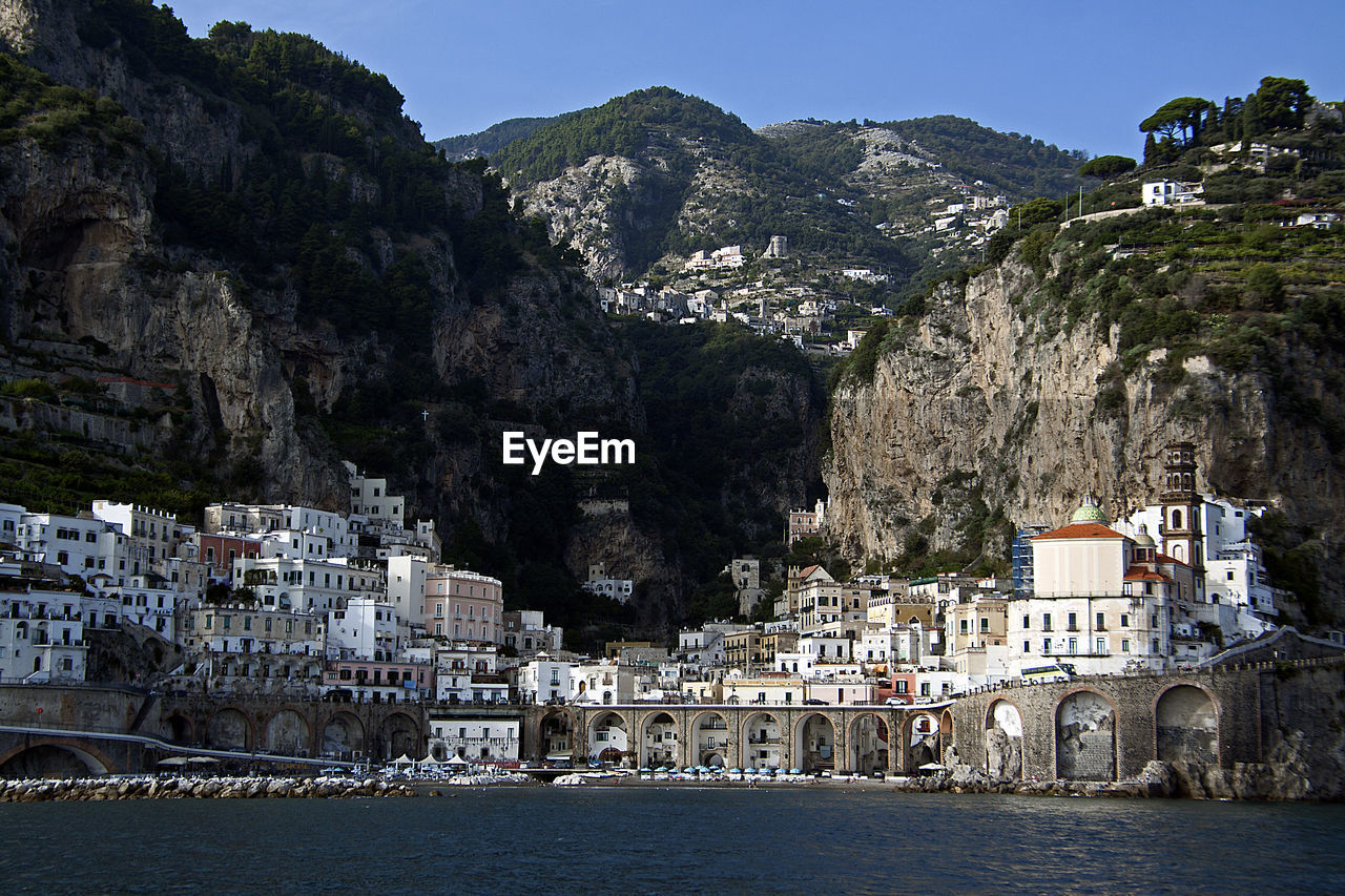 Town by sea and mountains against sky