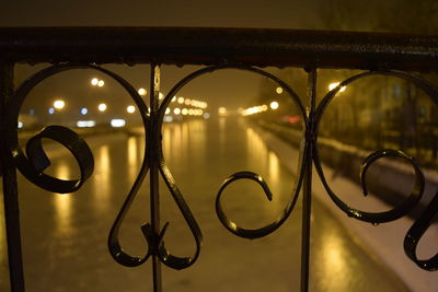 Lit lights along blurred lake with railings in foreground