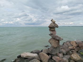 Rocks on shore by sea against sky