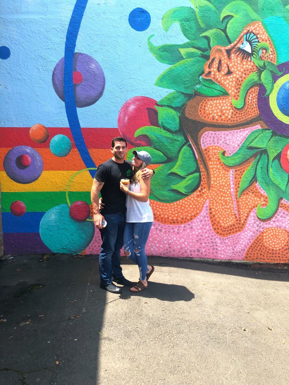 two people, full length, art and craft, creativity, men, multi colored, standing, real people, casual clothing, representation, togetherness, day, women, adult, males, people, graffiti, young adult, wall - building feature, love, outdoors, mural, positive emotion