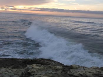 Waves splashing on rocks at sunset