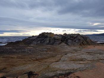 Rock formation on beach against sky