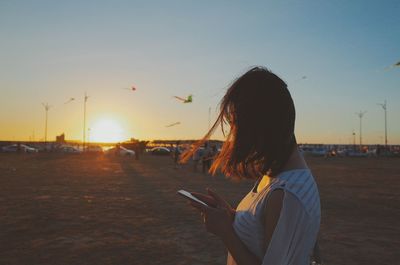 Woman using smart phone beside parking lot