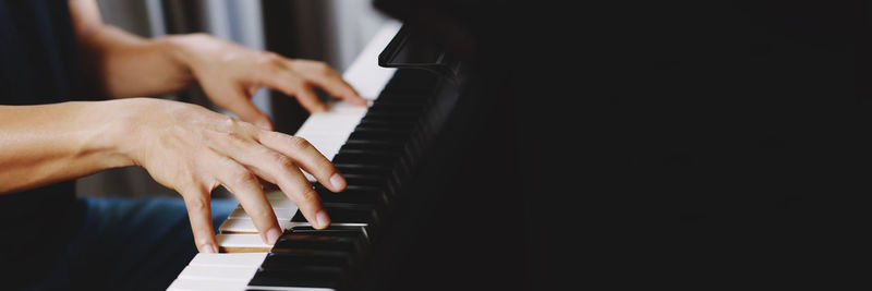 Cropped hands of woman playing piano