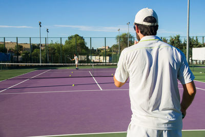 Male friends playing tennis on court