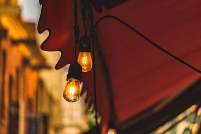 Low angle view of illuminated light bulb hanging from ceiling