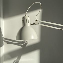 Close-up of light bulb hanging against wall at home