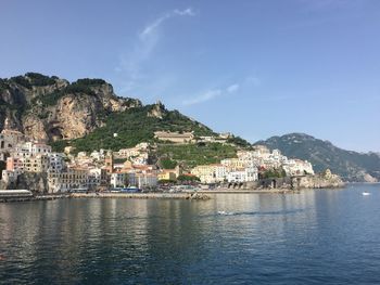 Buildings on mountain by river against sky at amalfi coast