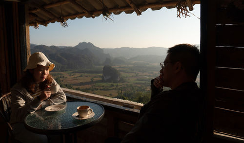 Couple sitting at restaurant against landscape