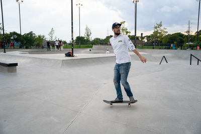 Full length of young man skateboarding on footpath