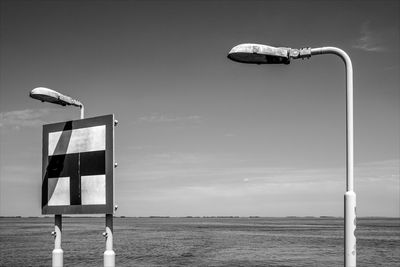 Street light on beach by sea against sky