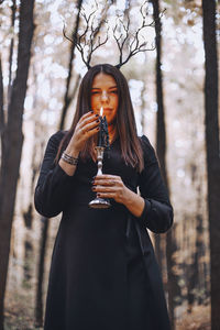 Portrait of young woman standing against trees