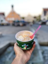 Midsection of person holding ice cream cone in city