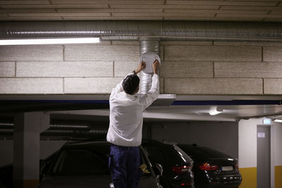 Rear view of man checking air duct