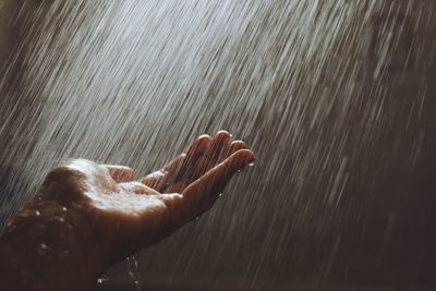 Cropped hand of person amidst rain