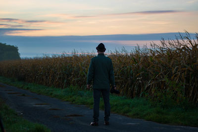 Rear view of man standing on field against sky