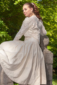 Beautiful woman standing by rock against trees