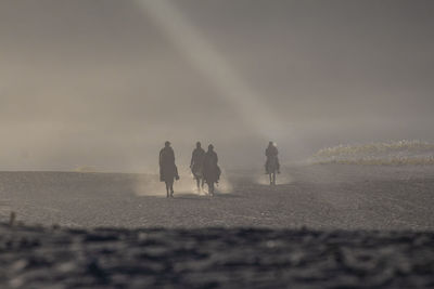 Silhouette people riding horse at desert