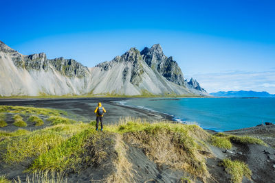 Rear view of man on shore against blue sky