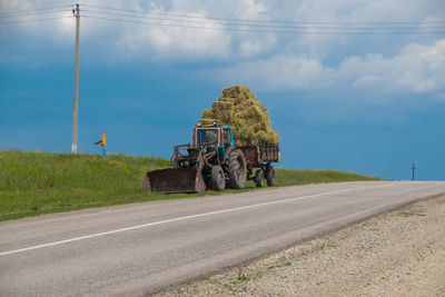 Road amidst agricultural field against sky