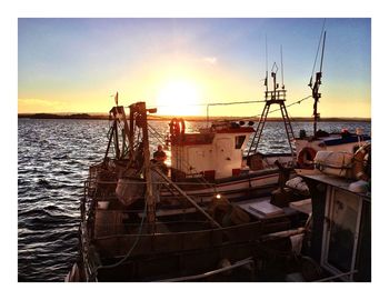 Boats in sea at sunset