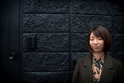 Young woman standing against wall