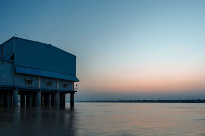 Building by sea against clear sky during sunset