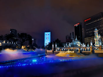 Illuminated city buildings against sky at night