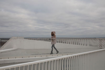 Woman standing on bridge against sky