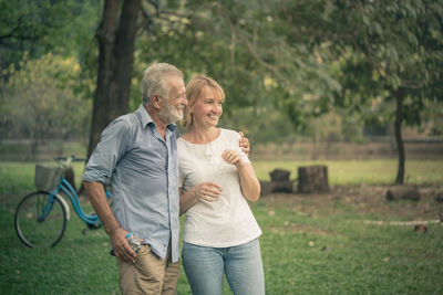 Happy friends sitting on grass against trees