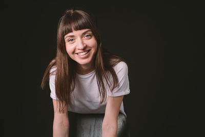 Portrait of a smiling young woman against black background
