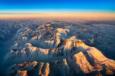 Aerial view of snowcapped mountains against sky during sunset