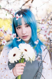 Portrait of beautiful woman standing by flowering plant