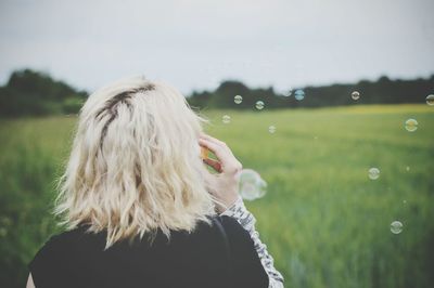 Rear view of woman by bubbles on field