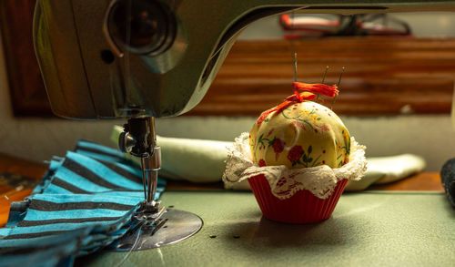 Pincushion in the shape of a cake or edible candy at the base of a sewing machine