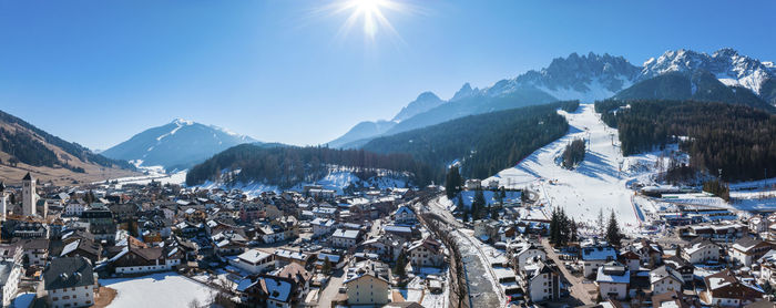 Panoramic view of sun shining over mountain range and townscape during winter