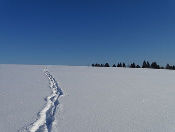Scenic view of snow covered land against clear blue sky