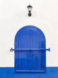 Simple blue locked window with a traditional lamp above in the streets of asilah
