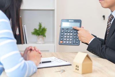 Midsection of woman holding smart phone on table