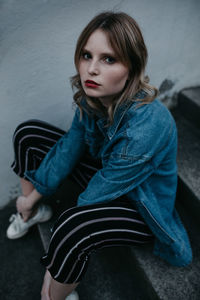 Portrait of woman wearing denim jacket sitting on steps