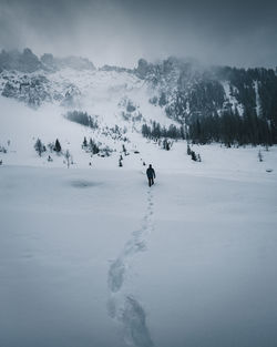 People on snow covered land against sky