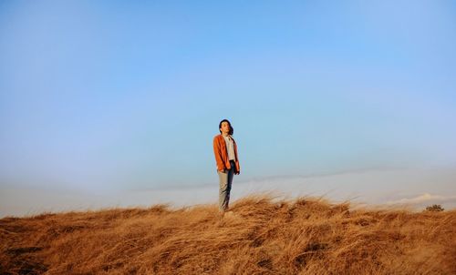 Portrait of man standing on field against clear sky