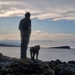 Rear view of man with dog standing on beach